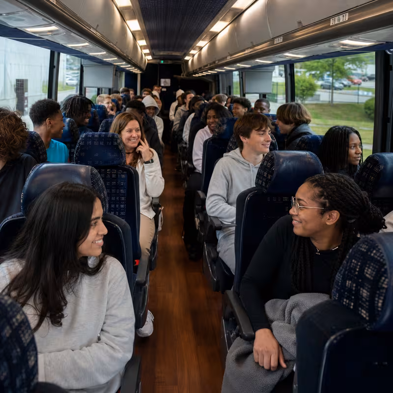 Group boarding a white charter bus for School Transportation transportation in New York